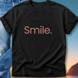 Black t-shirt with "Smile." in pink text, worn by a person.