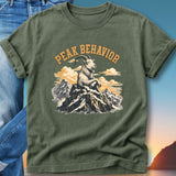 Green t-shirt with "Peak Behavior" text and mountain goat on rocky peak.