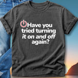 Black t-shirt with white text "Have you tried turning it on and off again?"