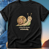 Black t-shirt with snail graphic and "Living the dream eventually" text.
