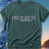 Green t-shirt with "PROGRESS not perfection" text, worn with jeans.
