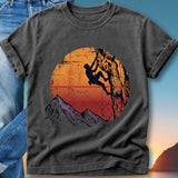 T-shirt graphic of a climber on a cliff face with a sunset and mountains.