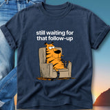 T-shirt with cartoon tiger lounging in chair, text "still waiting for that follow-up".