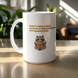 White mug with raccoon reading a book and text.