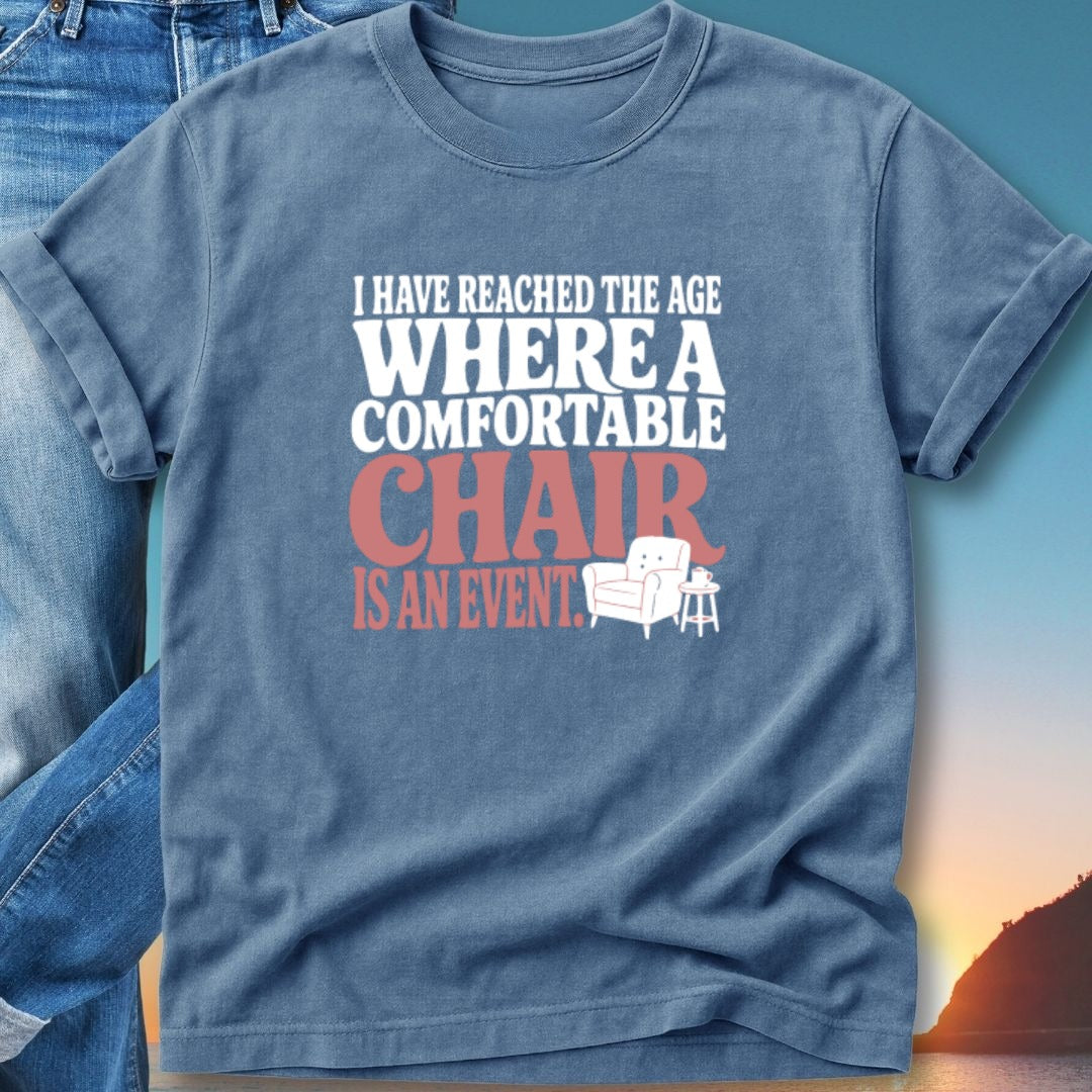 Blue t-shirt with "I have reached the age where a comfortable chair is an event" text.