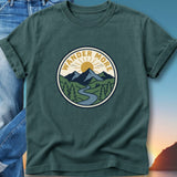 T-shirt with circular nature graphic: sun, mountains, river, and text "WANDER MORE".