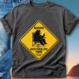 Yellow diamond sign with bear sitting in chair using phone, text "WARNING BEAR SCROLLING PHONE PROCEED WITH CAUTION".