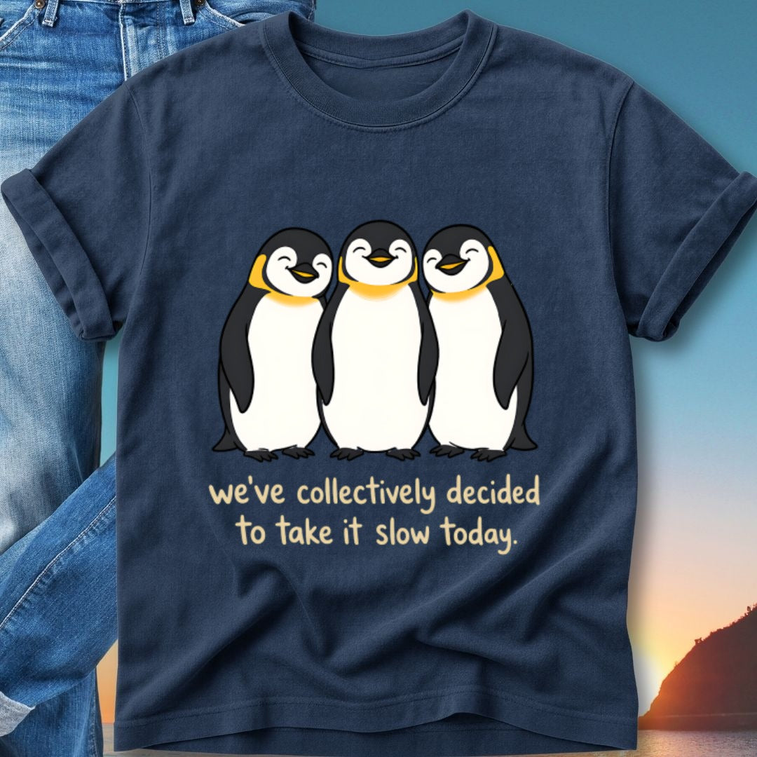 Three cartoon penguins on a navy t-shirt with text "we've collectively decided to take it slow today."