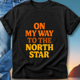 Black t-shirt with orange and yellow text that says "On My Way To The North Star".