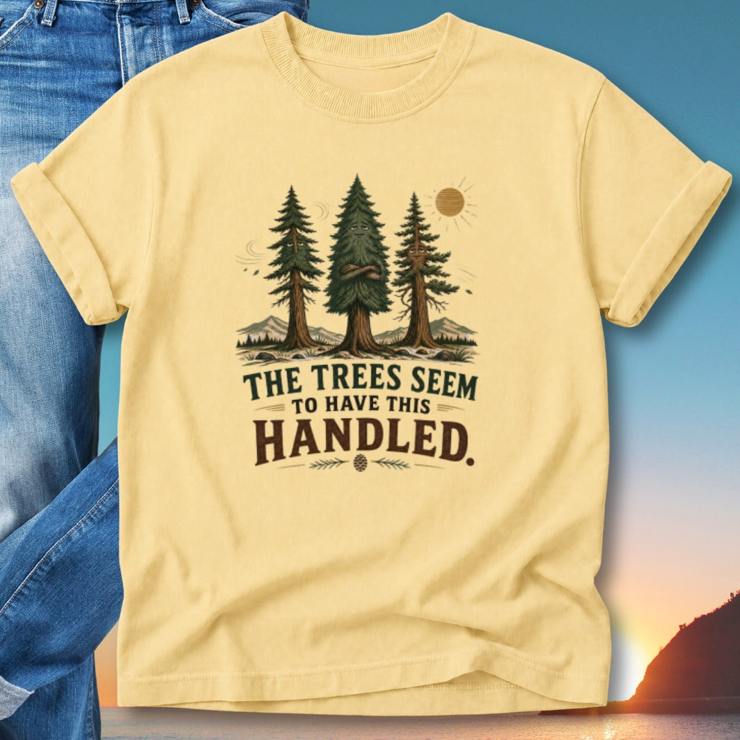 Yellow t-shirt with "The Trees Seem To Have This Handled" text and pine trees graphic.