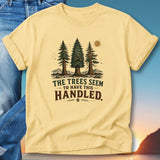 Yellow t-shirt with "The Trees Seem To Have This Handled" text and pine trees graphic.