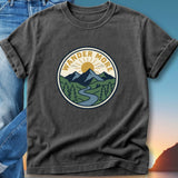 Graphic t-shirt with "Wander More" text in a circular mountain landscape design.