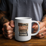 White mug with "Strange things happen before coffee" text.
