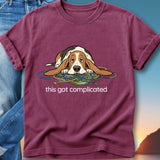 Burgundy t-shirt with a cartoon dog tangled in colorful cords, text says "this got complicated."