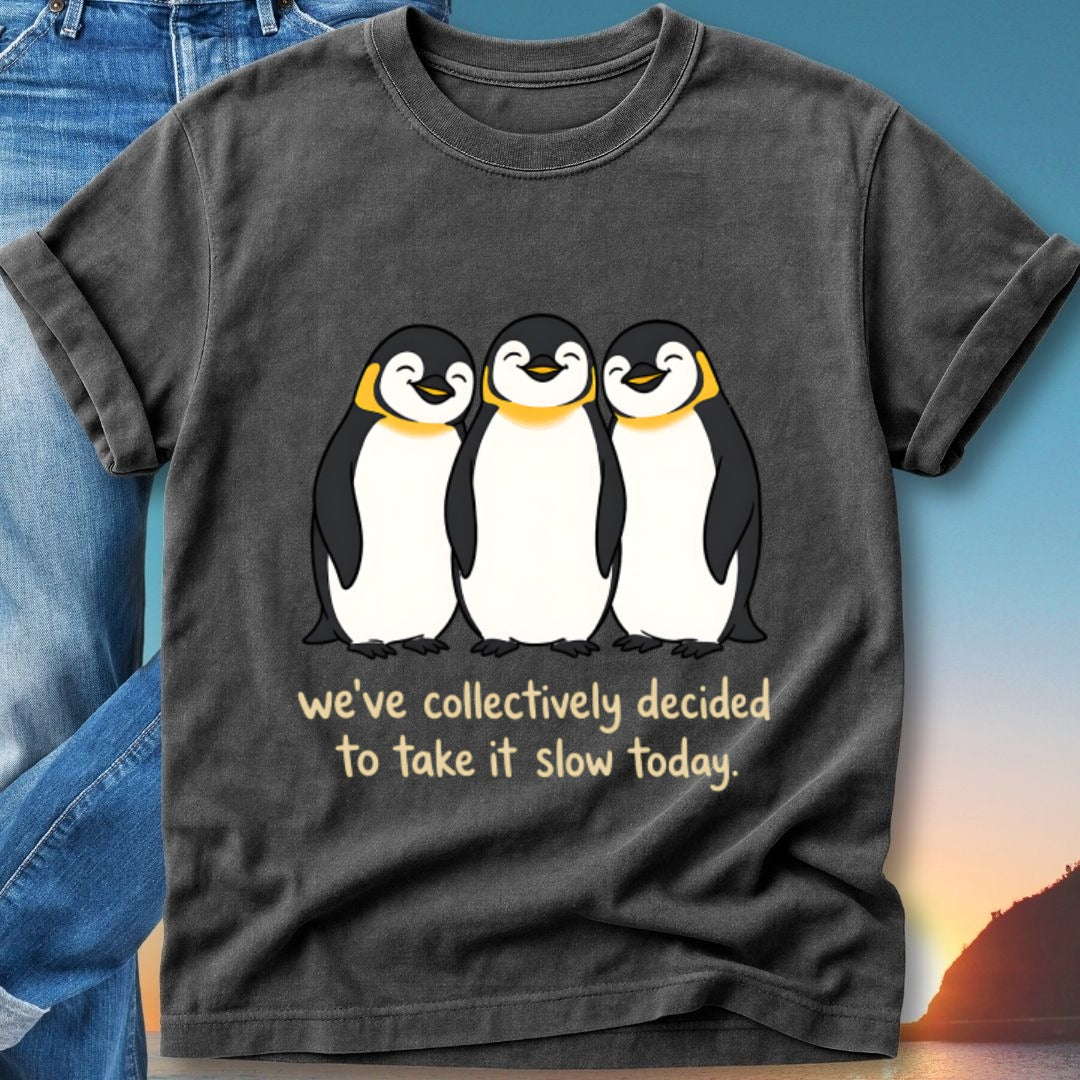 Three smiling penguins on a dark t-shirt with text "we've collectively decided to take it slow today."