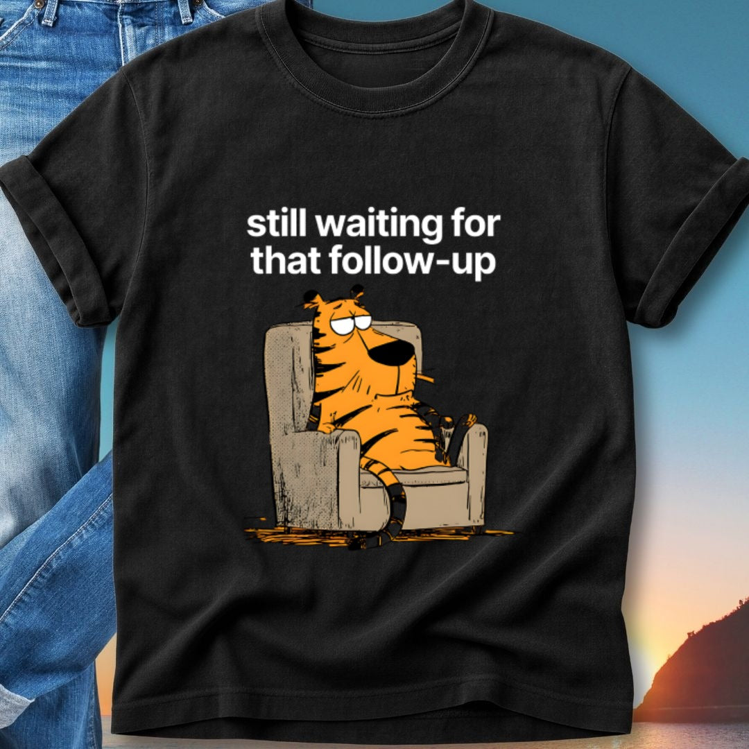 Black t-shirt with cartoon tiger sitting in armchair, text "still waiting for that follow-up".