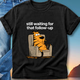 Black t-shirt with cartoon tiger sitting in armchair, text "still waiting for that follow-up".