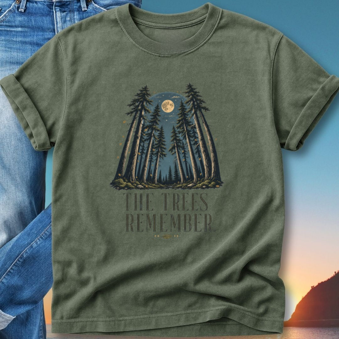 Olive green t-shirt with tall trees under a full moon and the text "THE TREES REMEMBER".