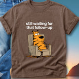 Brown t-shirt with cartoon tiger sitting in armchair, text "still waiting for that follow-up".