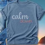 Blue t-shirt with "calm down." text, against a sunset backdrop.