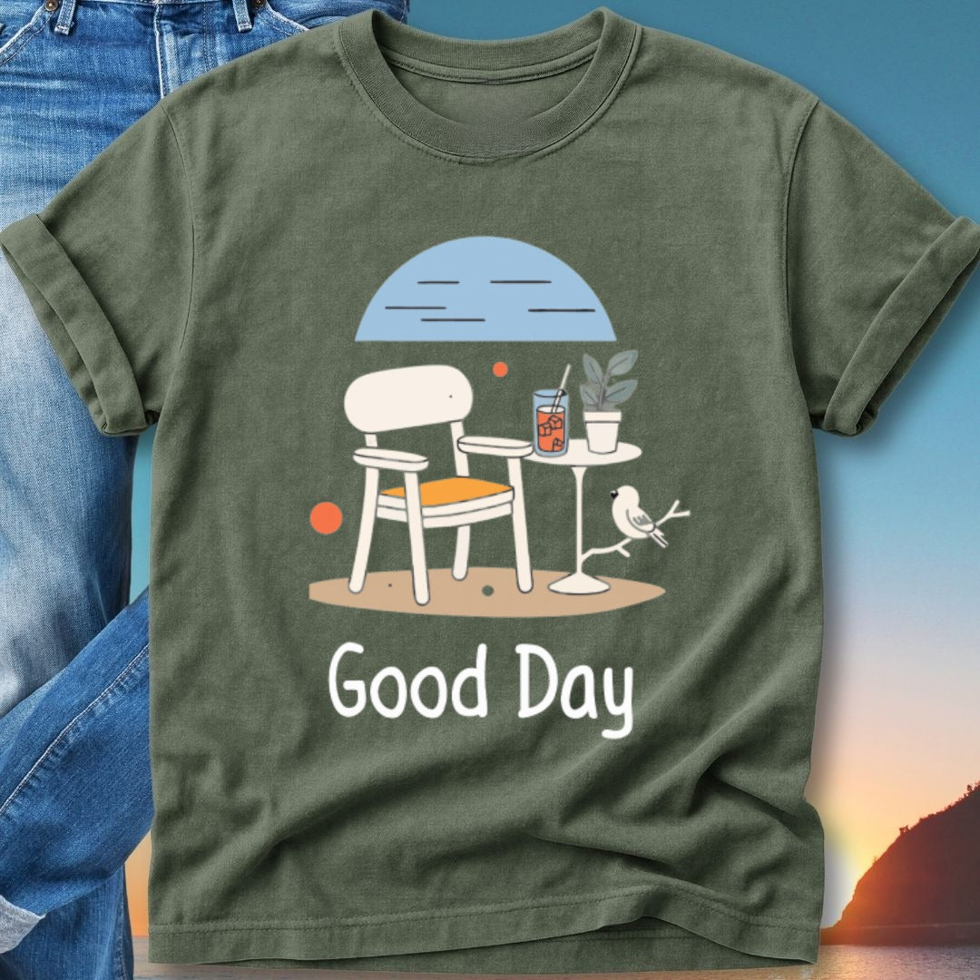 Green t-shirt with illustration of chair, table, drink, bird, and text "Good Day".