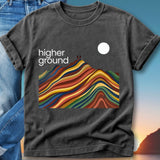 Dark t-shirt with colorful mountain range graphic and "Higher Ground" text.
