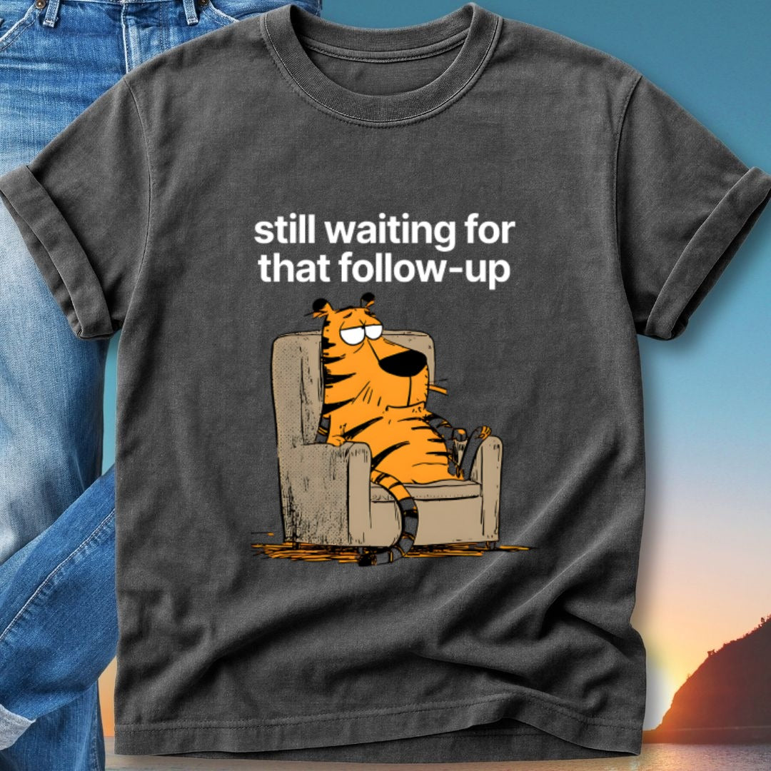 T-shirt graphic: orange tiger sitting in chair, text "still waiting for that follow-up".